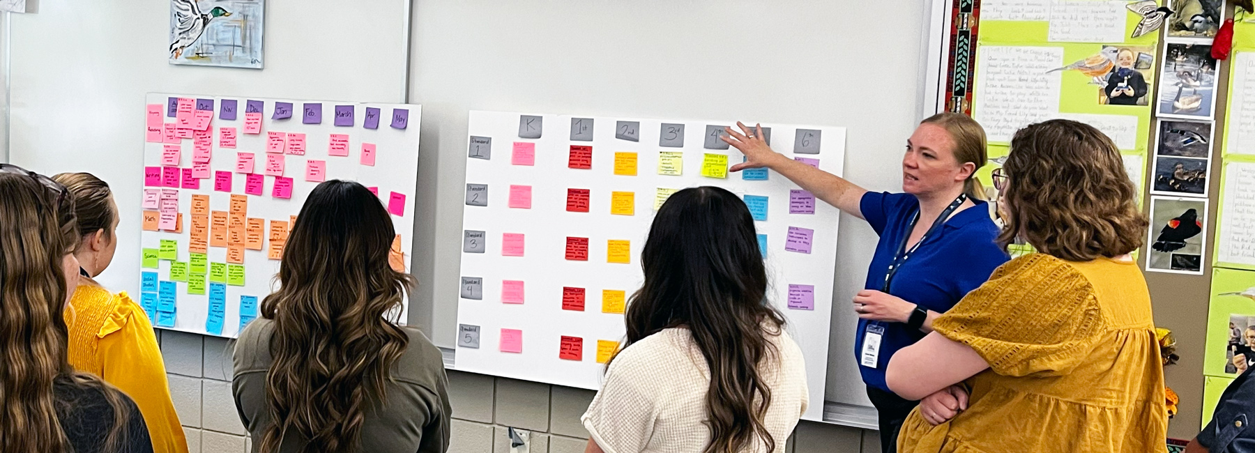 A teacher pointing at white board post-it notes.