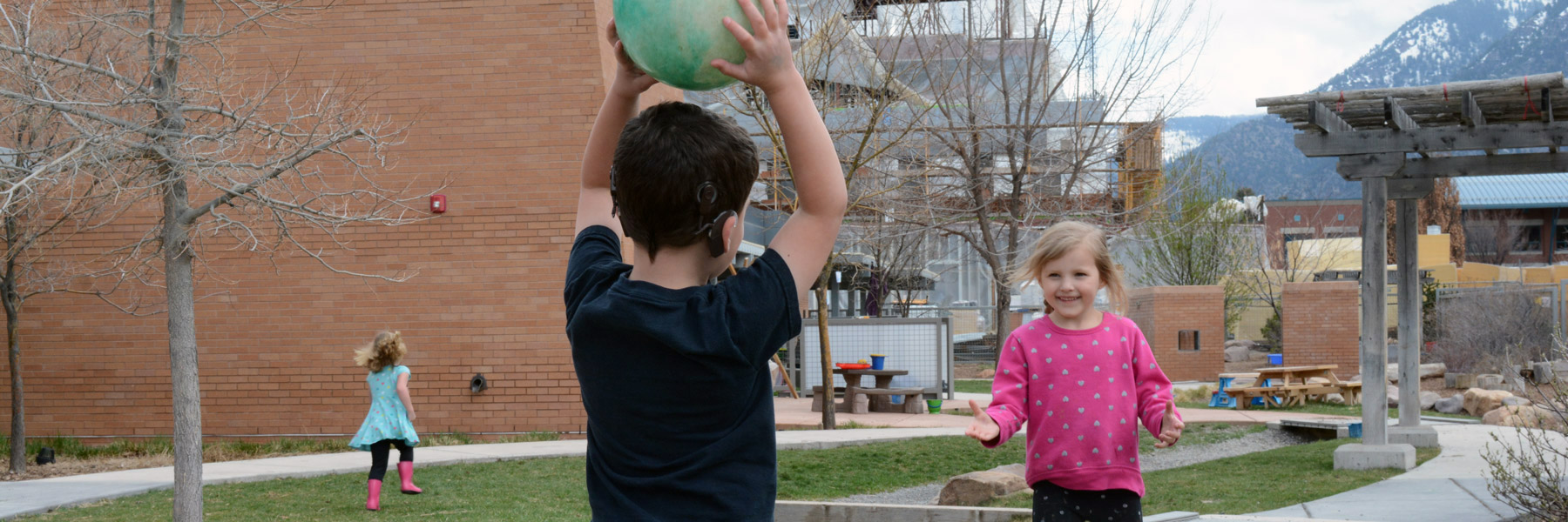 A boy and a girl playing outside with ball.