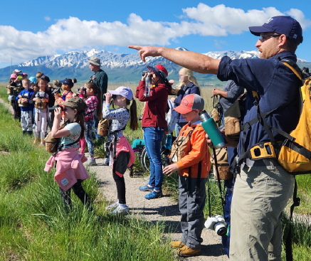 A teacher leads students in outdoor learning activities.