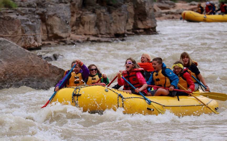 A group of 6th-grade students and chaperones floating in a water raft on the San Juan River.