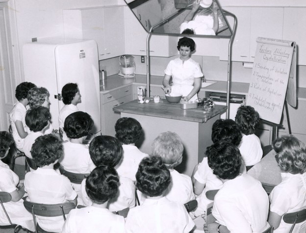 This is a photo of two instructors giving a lecture in a home economics class in the 1950's.