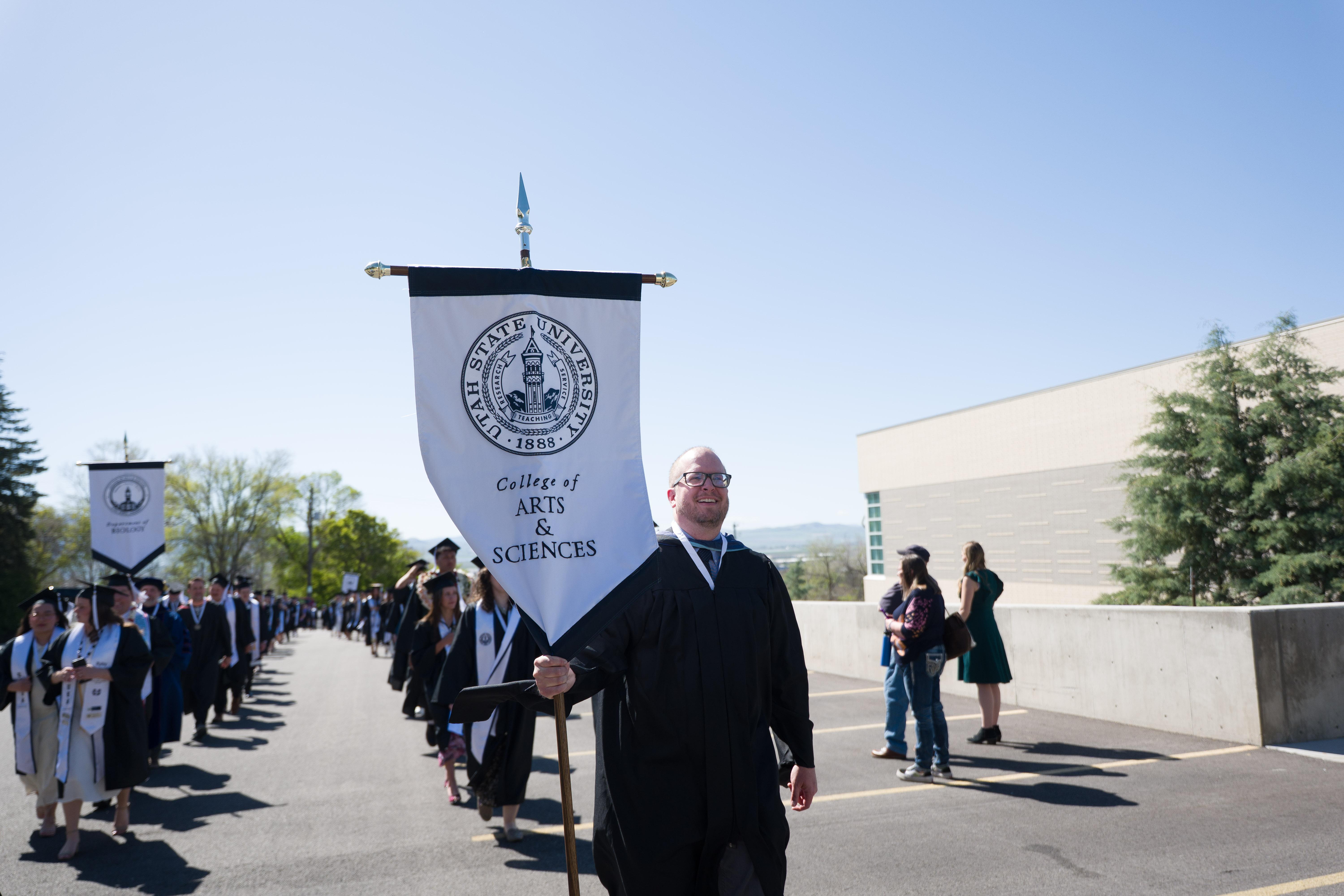 college of ArtSci banner held by graduate leading the processional