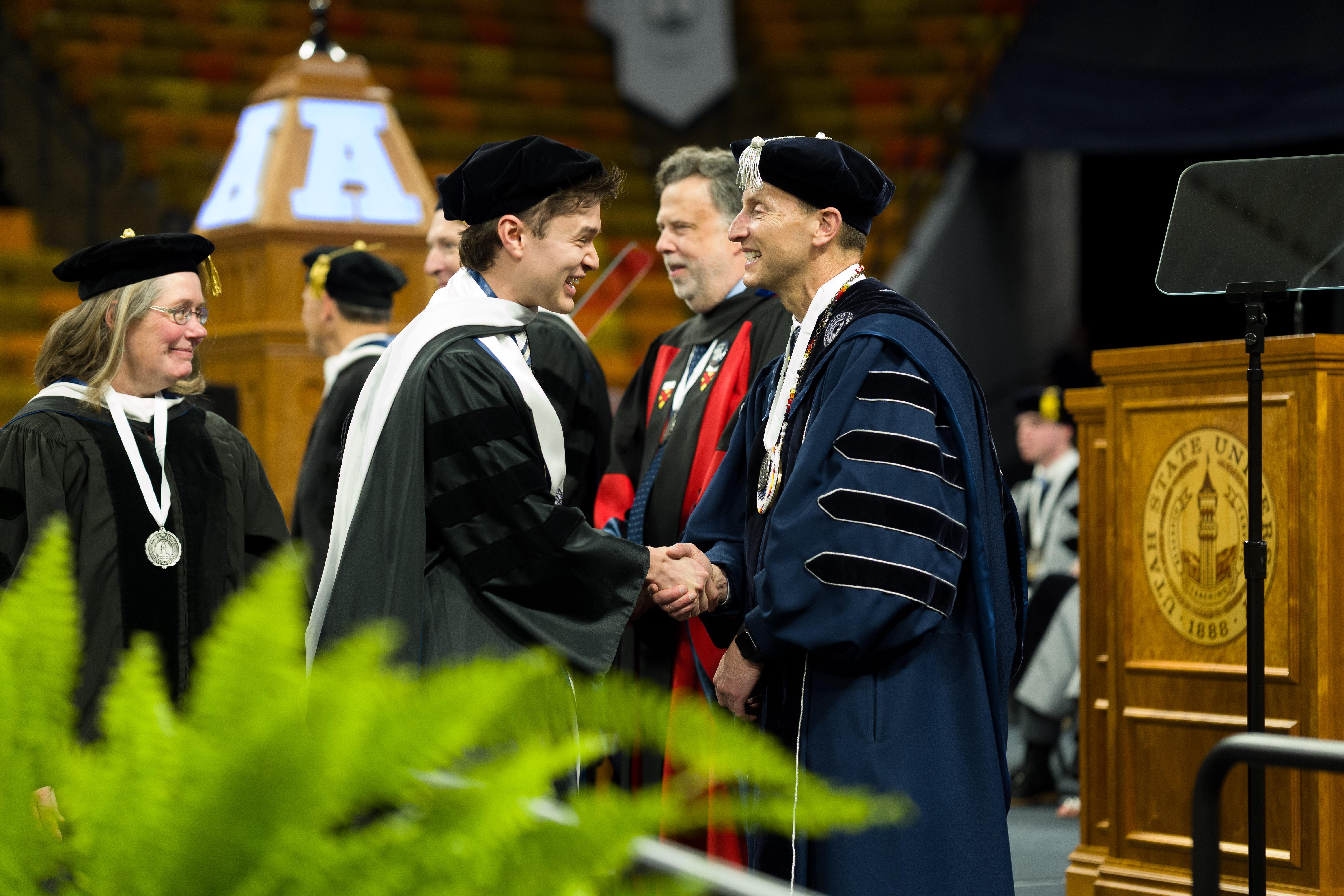 graduates shaking hands while receiving diplomas