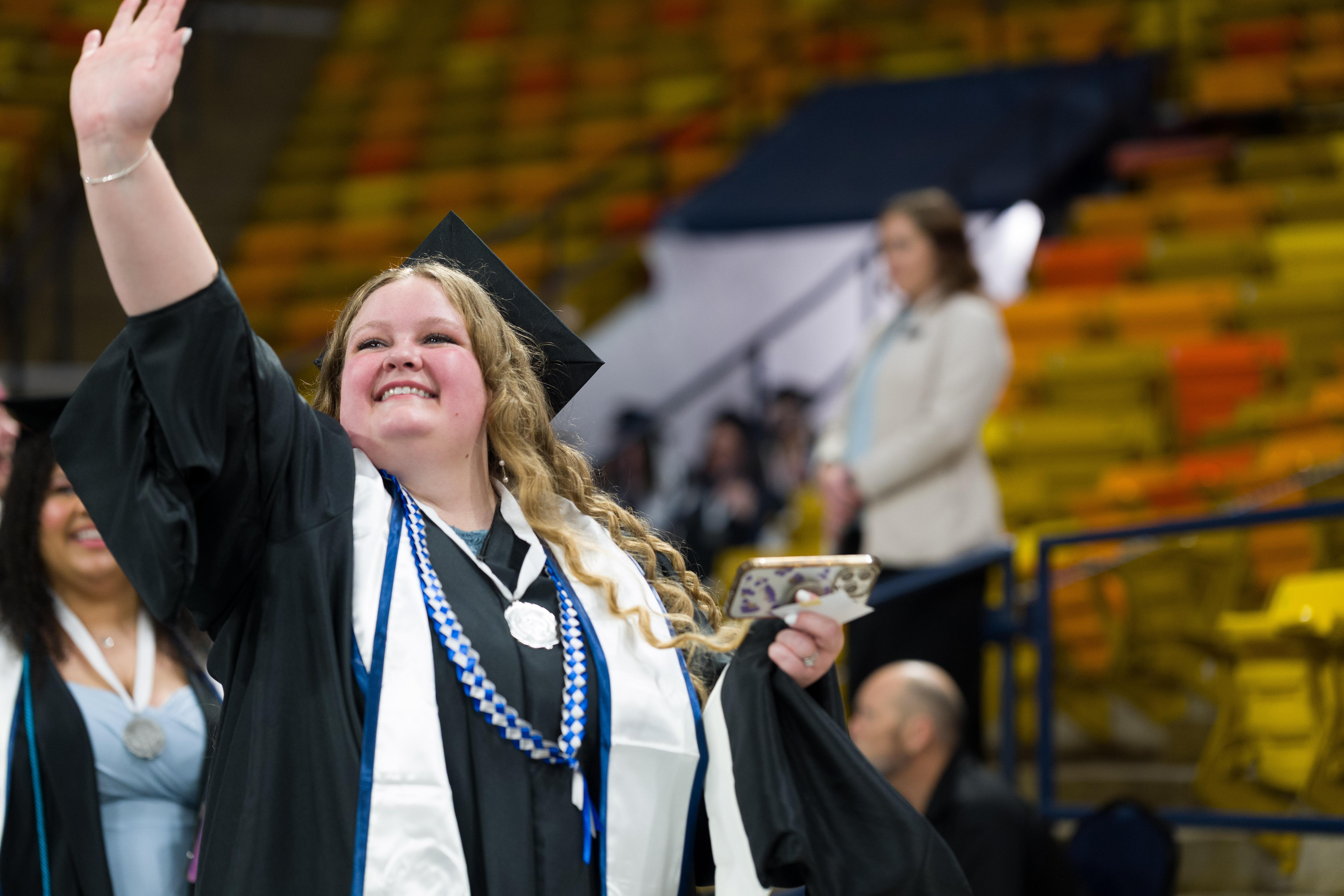 graduate waving to the audience