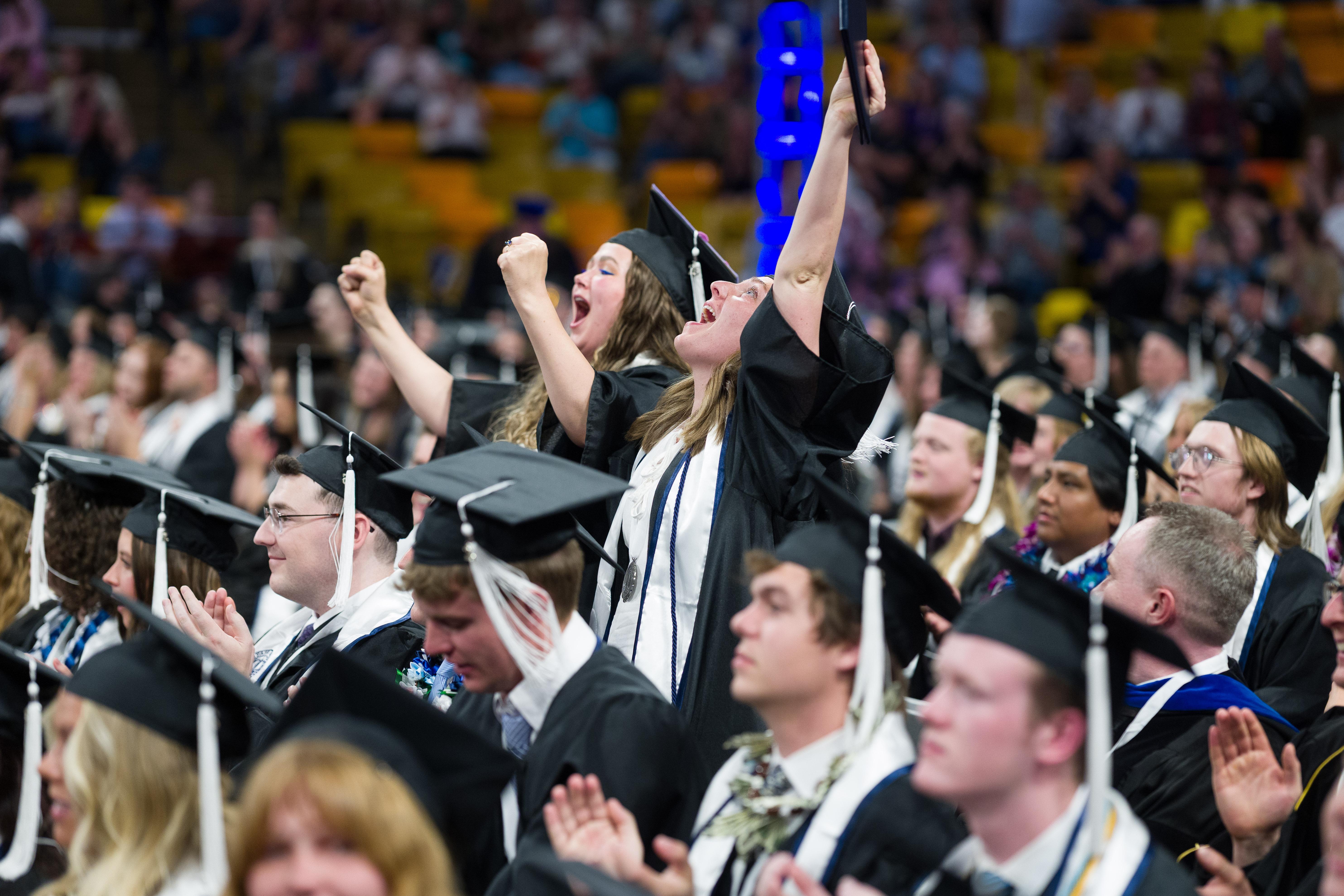 graduates cheering with arms in the air