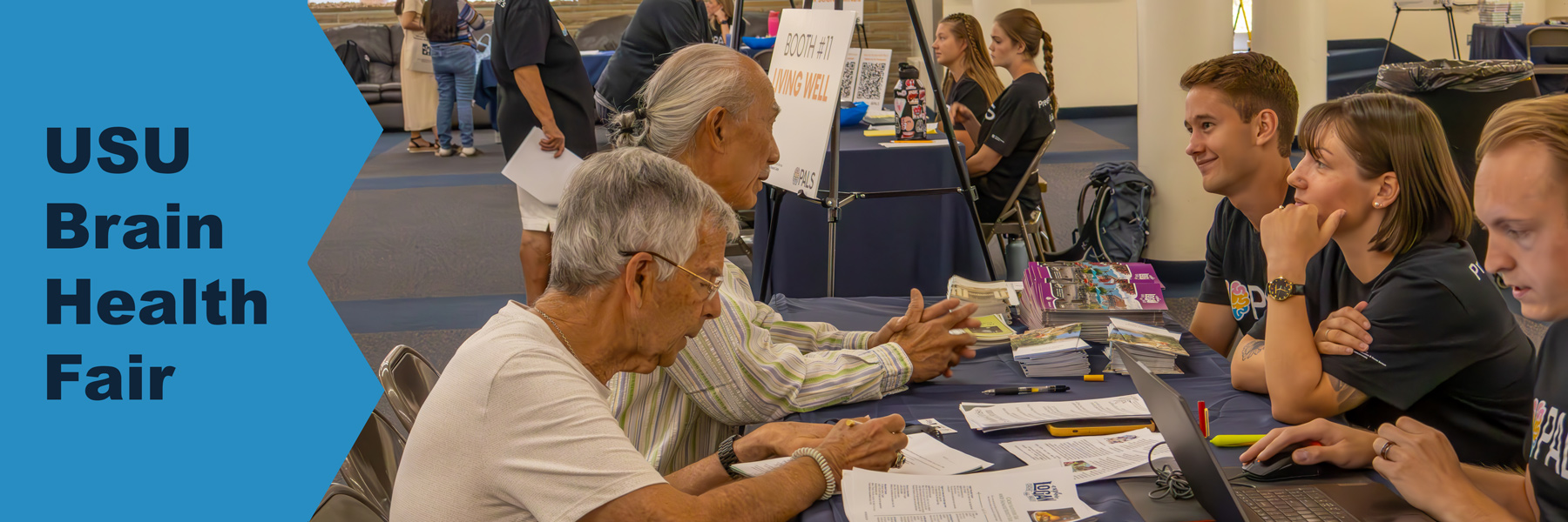 2 men at a booth talking to vendors at Brain Health Fair.