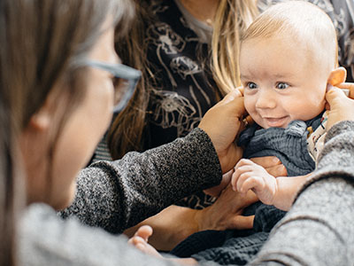 A clinician holding a hearing device to a baby's ears
