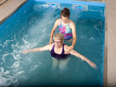 Therapist and patient talking in a pool doing physical therapy