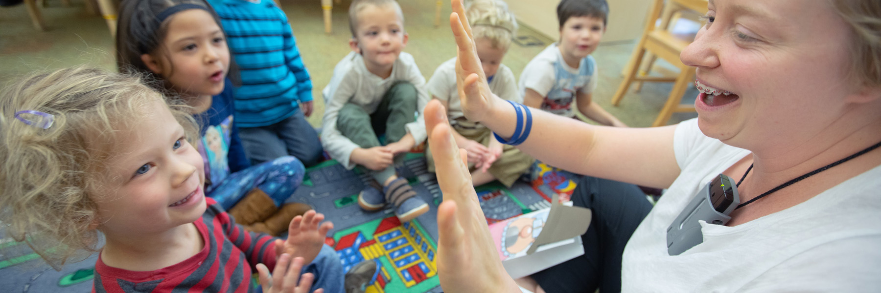 Teacher in a classroom laughing with kids.